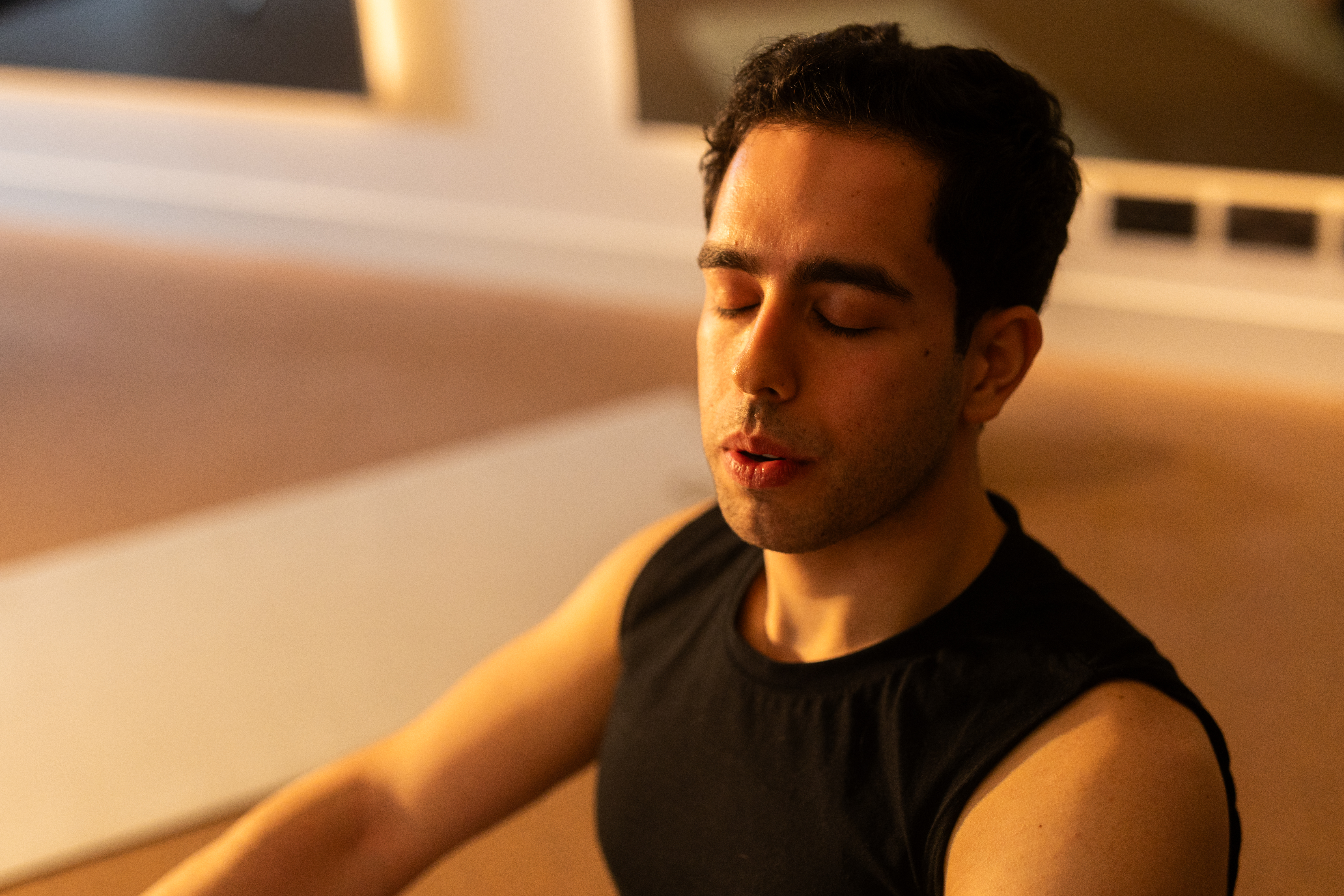A male gym member taking a deep breath during a yoga class. 