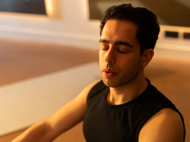 A male gym member taking a deep breath during a yoga class.