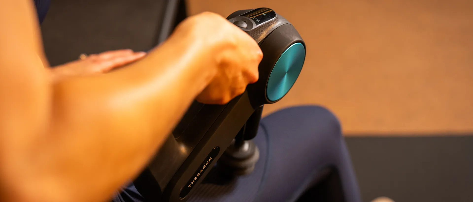 A member using a massage gun to perform Percussion Stretch Therapy