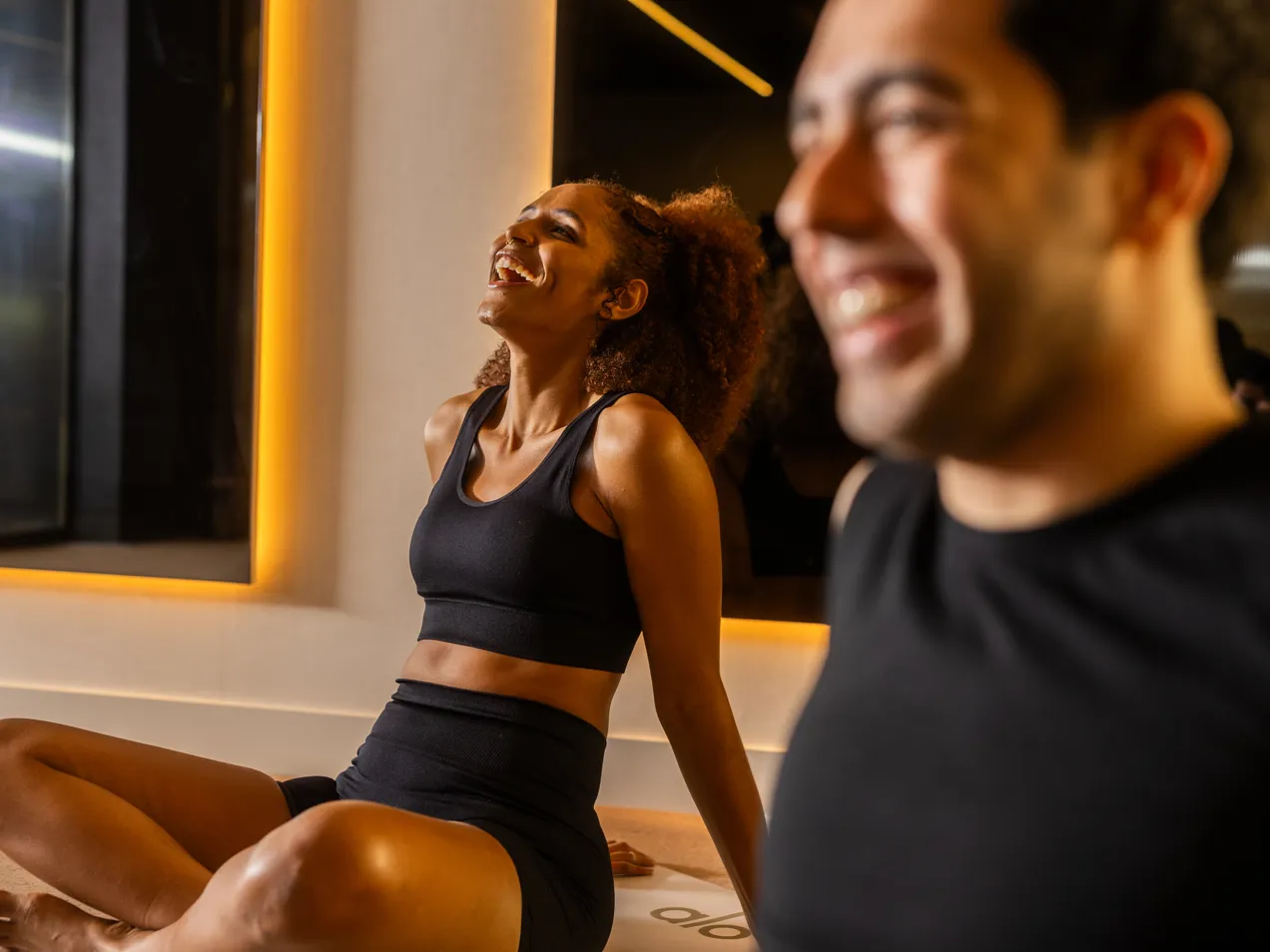 Two members talking and laughing during their yoga class.