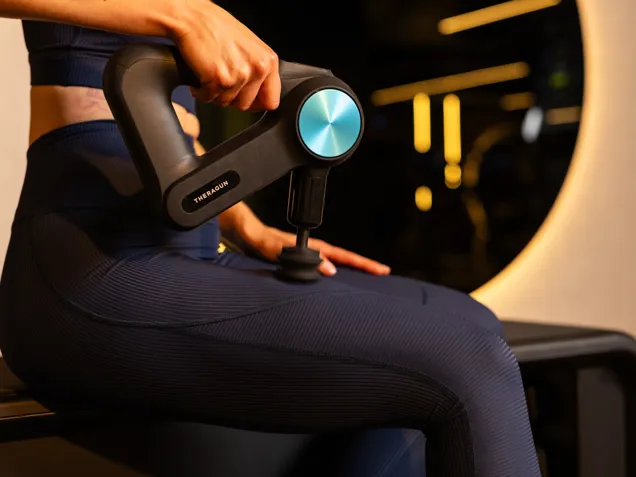 A member using a massage gun on their quad.